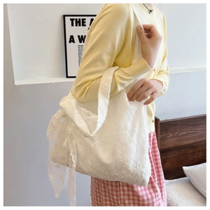 Close-up of intricate white lace floral embroidery on a large canvas tote bag