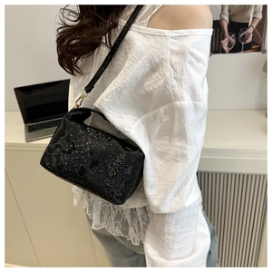 Detail view of large black snakeskin pattern shoulder bag with golden metal hooks