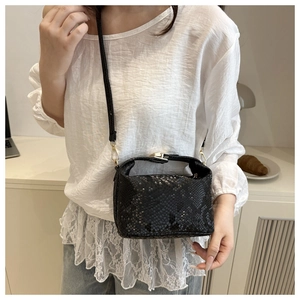 Close-up of black snakeskin pattern crossbody bag with golden metal hooks and fine strap