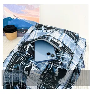 Detail of the front zipper pocket on denim plaid backpack holding a smartphone