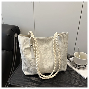 Close-up of beige lace tote bag featuring 3D butterfly embroidery and fringe charms
