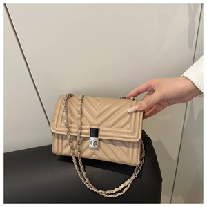 Close-up of beige quilted crossbody bag with V-shaped stitching and silver metal lock