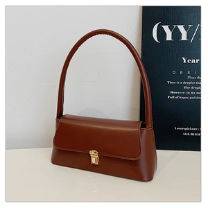 Détail du sac baguette marron foncé minimaliste avec boucle dorée et texture cuir