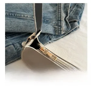 Detailed close-up of premium smooth metal zipper on off-white pebbled leather baguette bag