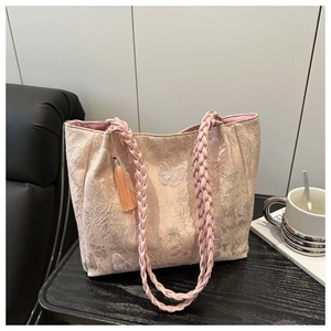 Detail of light pink lace tote bag featuring white butterfly embroidery and braided handles