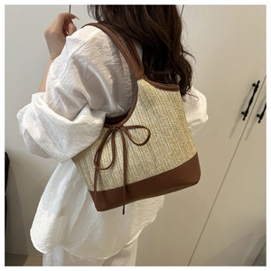Detail of bohemian straw woven tote bag featuring dark brown leather straps and bow tie