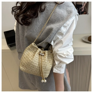Detailed view of beige woven bucket bag with pearl drawstring and gold chain strap