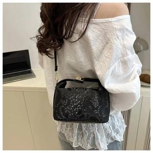 Detail of black snakeskin texture leather bag with elegant gold metallic hardware buckle