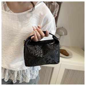 Close-up of black snakeskin texture and metal zipper on this designer mini handbag