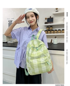 Detail of green plaid backpack featuring spacious pockets and soft knotted zipper pulls