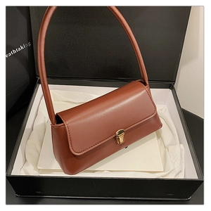 Sac à bandoulière en cuir caramel avec fermoir doré dans un coffret cadeau noir de luxe