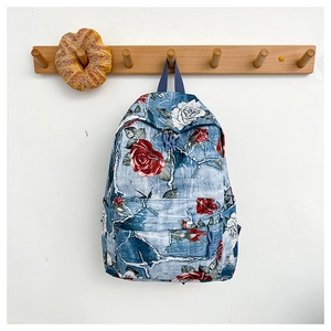 Detail of floral canvas backpack with red rose prints hanging on a wooden hook