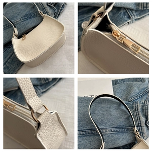 Detail view of white lychee leather texture and golden metal zipper on baguette bag