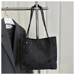 Macro shot of black jacquard tote bag with butterfly embroidery and woven handles