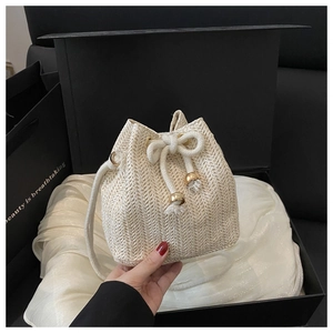 Detail der beige handgewebten Stroh-Beuteltasche mit Kordelzug-Quasten und goldener Hardware