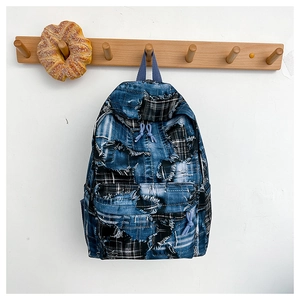 Detail view of denim patchwork backpack with distressed edges and blue zipper pulls