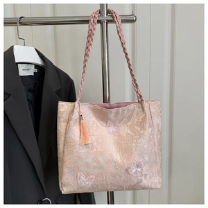 Detail of pink tote bag featuring 3D butterfly embroidery and woven handle with silk tassels