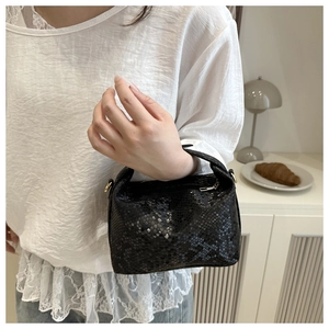 Detail view of black snakeskin texture handbag with premium gold-tone metal zipper and hardware