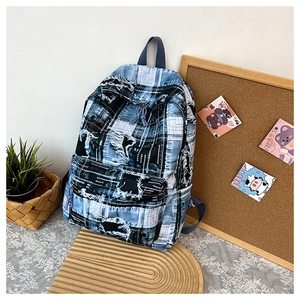 Detail of distressed patchwork backpack with blue plaid denim and raw edges in a cozy setup