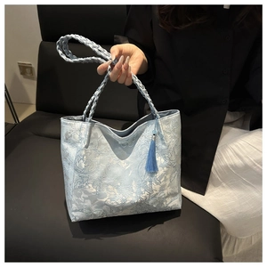 Detail of light blue silk tote with floral embroidery and elegant tassel charm