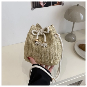 Nahaufnahme der handgefertigten Strohtasche mit weißem Kordelzug und goldenen Perlen
