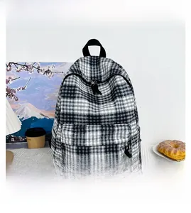 Detailed close-up of a black and white checkered backpack featuring a large front zipper pocket