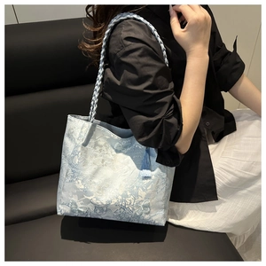 Close-up of light blue jacquard tote bag with floral embroidery and woven strap
