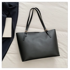 Detailed shot of a black tote bag with premium leather texture and gold buckle accents