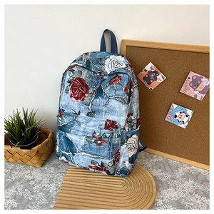 Detail of floral canvas backpack featuring red rose print and front zipper pocket