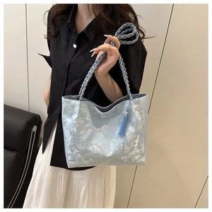 Detail of light blue lace tote bag with floral jacquard texture and braided handles