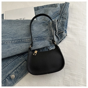 Detail der schwarzen Kieselleder-Textur an der halbmonden Schultertasche mit Gold-Hardware
