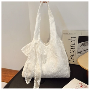 Detail of white floral lace tote bag with large decorative bow on the side and hand strap