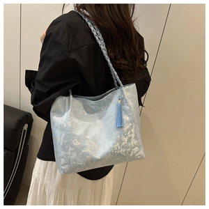 Detail of light blue embroidered tote bag with white butterfly patterns and elegant side fringe