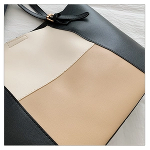 Close-up of tricolor stitching and pebbled leather texture on a stylish tote bag