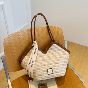 Large hand-woven straw tote bag with brown leather handles and sporty logo patch