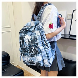 Detail of blue and white checkered canvas backpack with distressed patches and large pocket