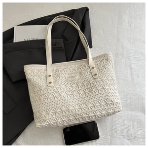Close-up of woven hollow tote bag with floral crochet pattern and brand logo plate