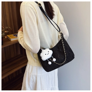Detail of black pleated shoulder bag with metal chain and cute white plush cloud charm