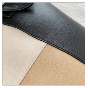 Detailed close-up of tri-color stitching and litchi texture on a large tote shoulder bag