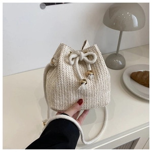 Detail einer cremefarbenen geflochtenen Beuteltasche mit Fischgrätmuster und Kordelzug