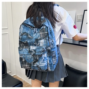 Detail of trendy denim patchwork backpack with frayed edges and dual-tone blue fabric