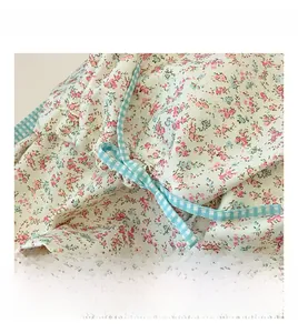 Close-up of floral pattern fabric with blue checkered trim and a decorative purple button