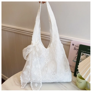 Detail view of white lace tote bag featuring floral embroidery and large bow accent