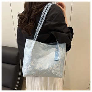 Detailed view of light blue tote featuring 3D butterfly jacquard and silk tassels
