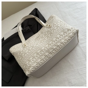 Detail of beige woven tote bag featuring intricate crochet texture and leather base design