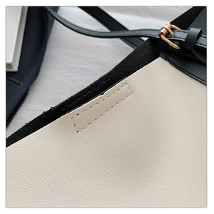 Detail of white lychee grain leather tote bag with black strap and gold buckle