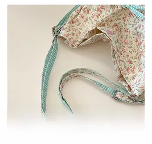 Detail shot of floral print backpack with light blue gingham shoulder strap and metal buckle
