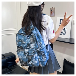 Detail of blue patchwork denim backpack with frayed edges and trendy knotted zipper ties