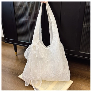 Detailed macro view of white floral lace embroidery and side ribbon bow on canvas tote