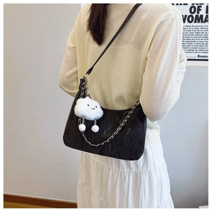 Close-up of black textured tote bag featuring a cute white cloud plush charm and chain strap